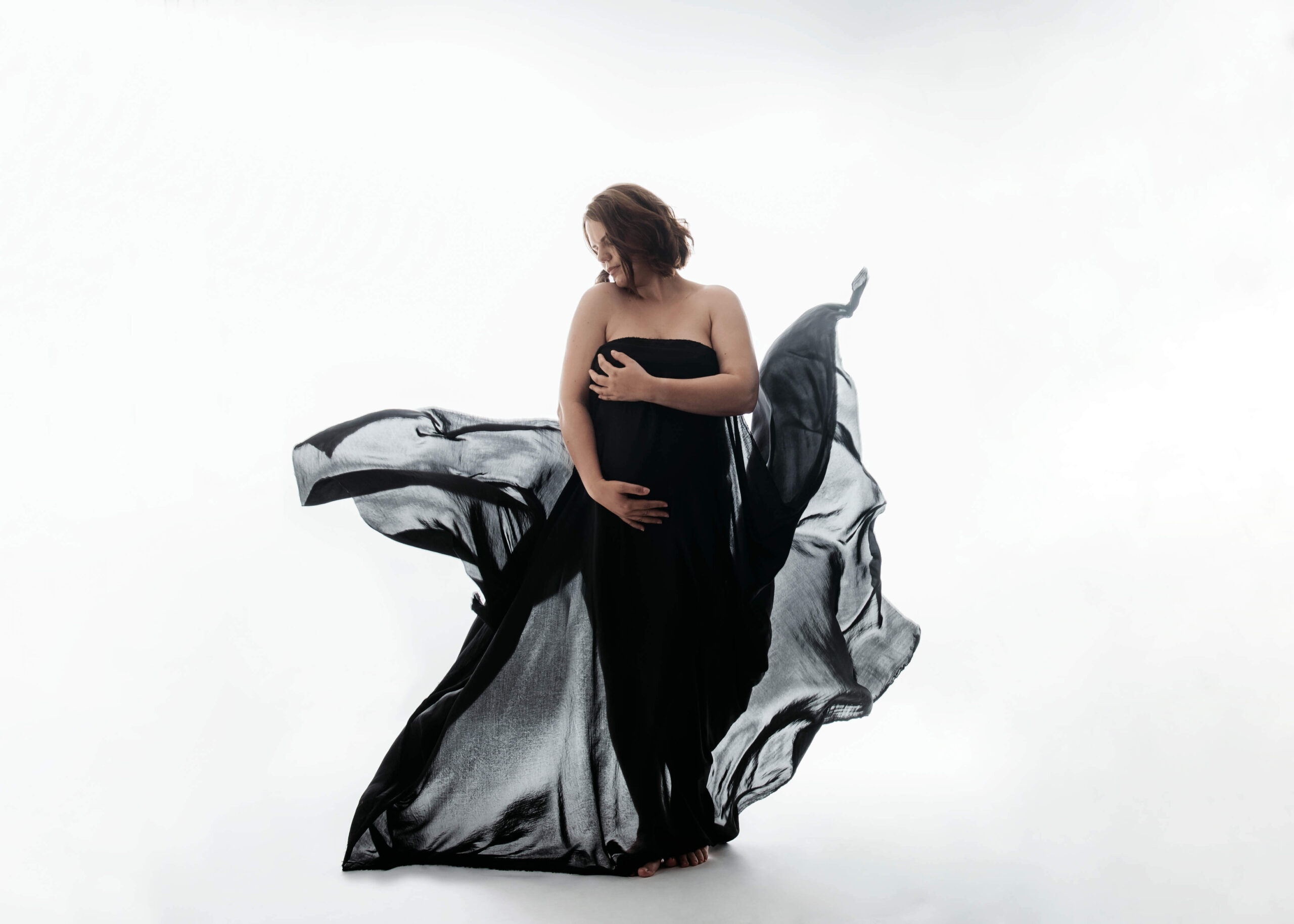 Schwangere mit einem schwarzem Tuch umhüllt